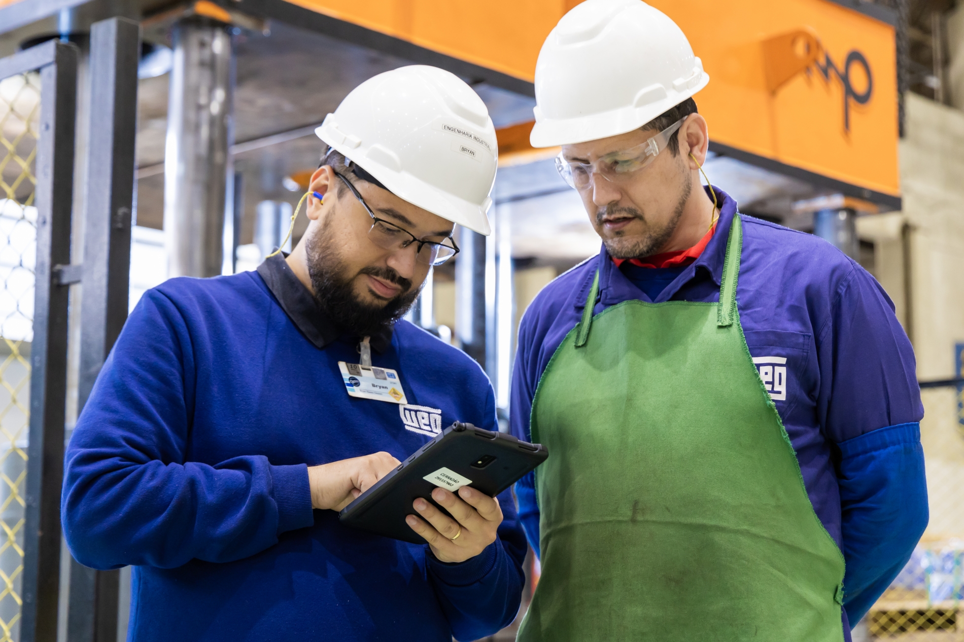 Engineers reviewing AC motor performance data for a DC vs AC motor evaluation in a factory.
