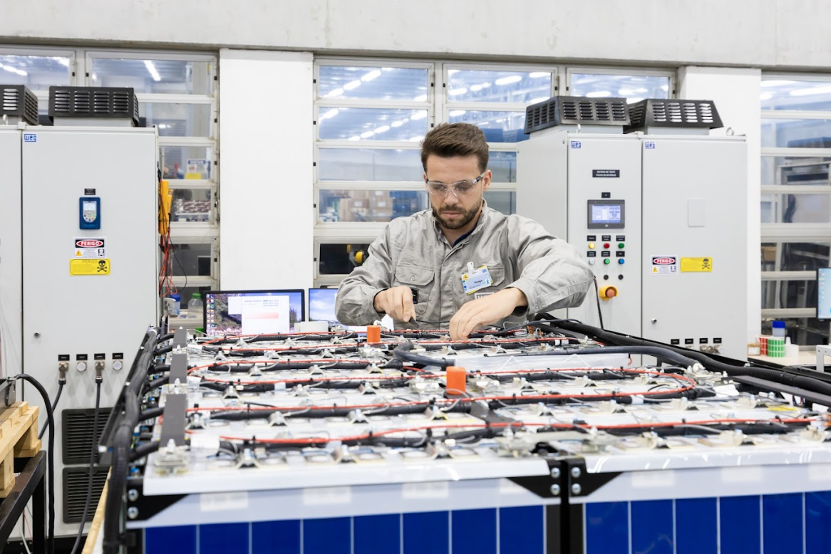 A technician in protective gear adjusting a WEG soft starter panel, ensuring smooth motor operation in an industrial automation set-up.