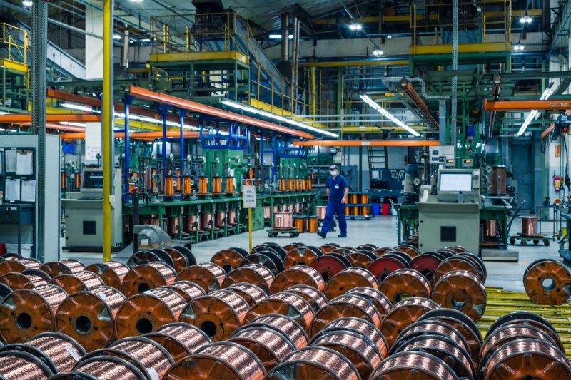 A large industrial facility with spools of copper wiring and machinery in operation, showcasing the scale of motor-driven production processes.