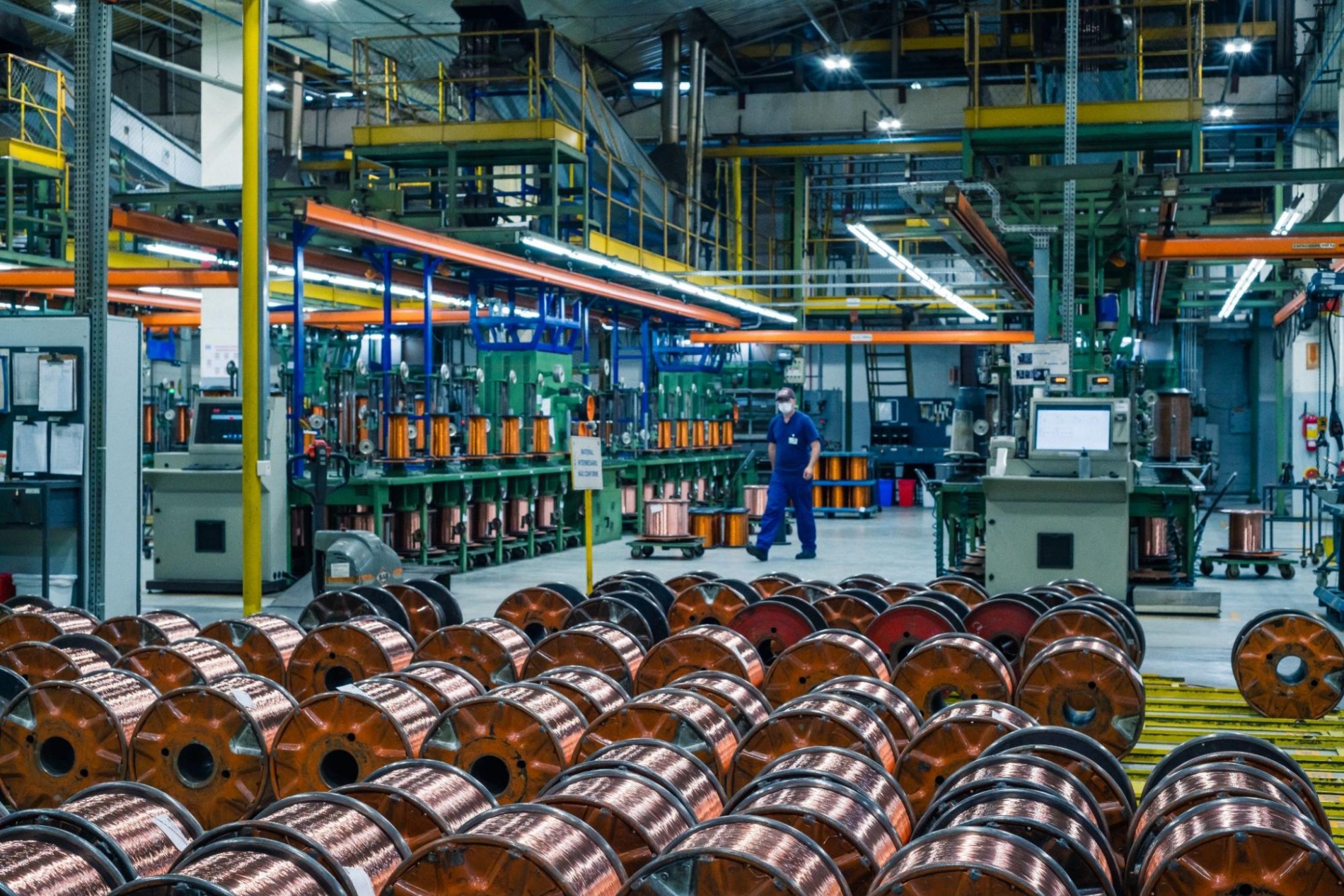 A large industrial facility with spools of copper wiring and machinery in operation, showcasing the scale of motor-driven production processes.