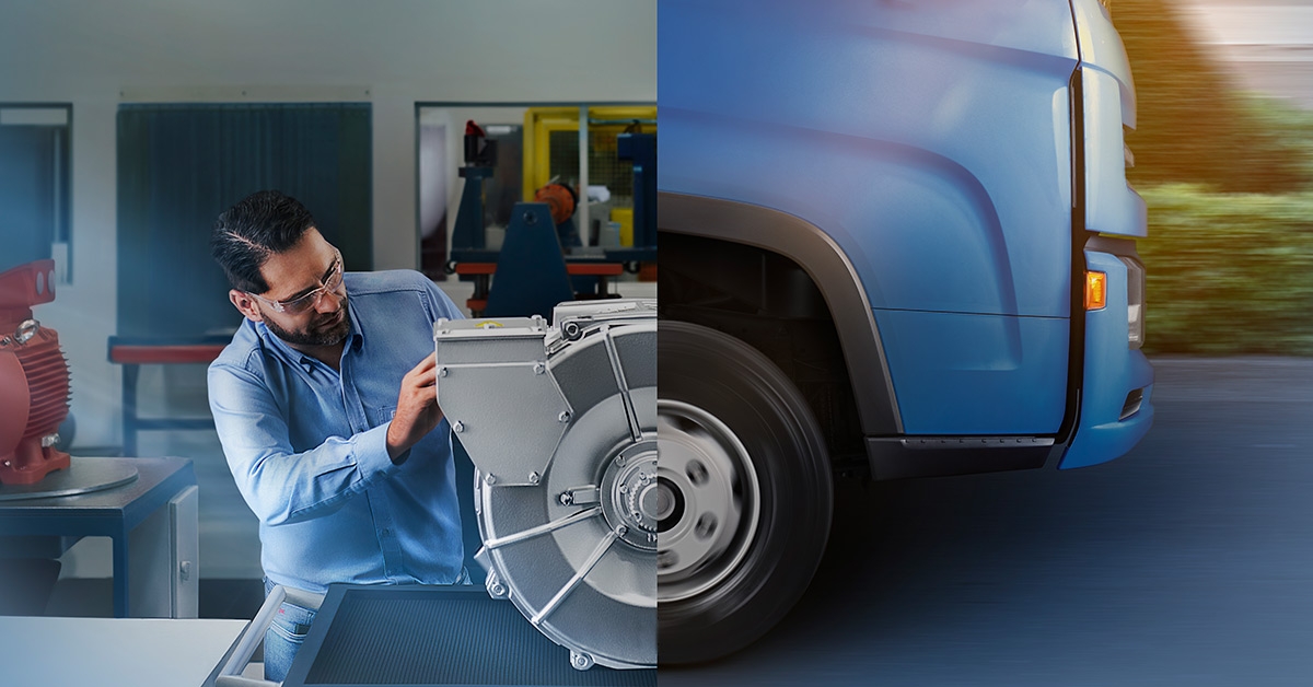 Engineer inspecting an electric motor beside a commercial vehicle wheel in an industrial automation lab setting.