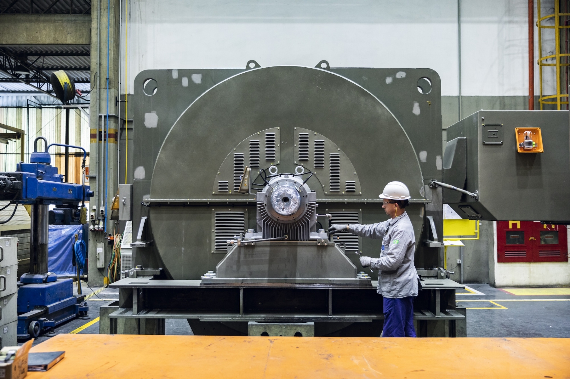 Industrial motor performance technician installing electric motor equipment inside a factory facility.