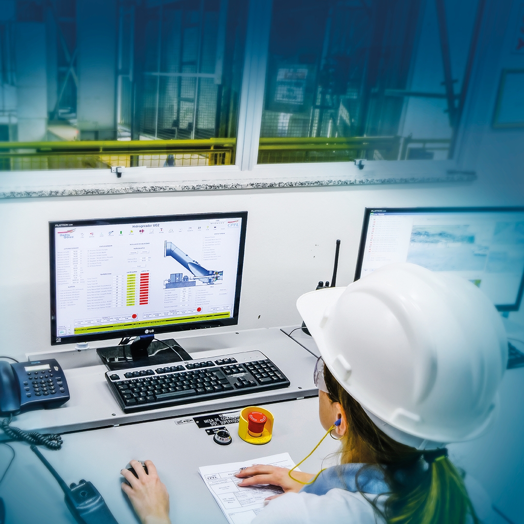Engineer monitoring induction motor control system data on dual screens at an industrial control station.