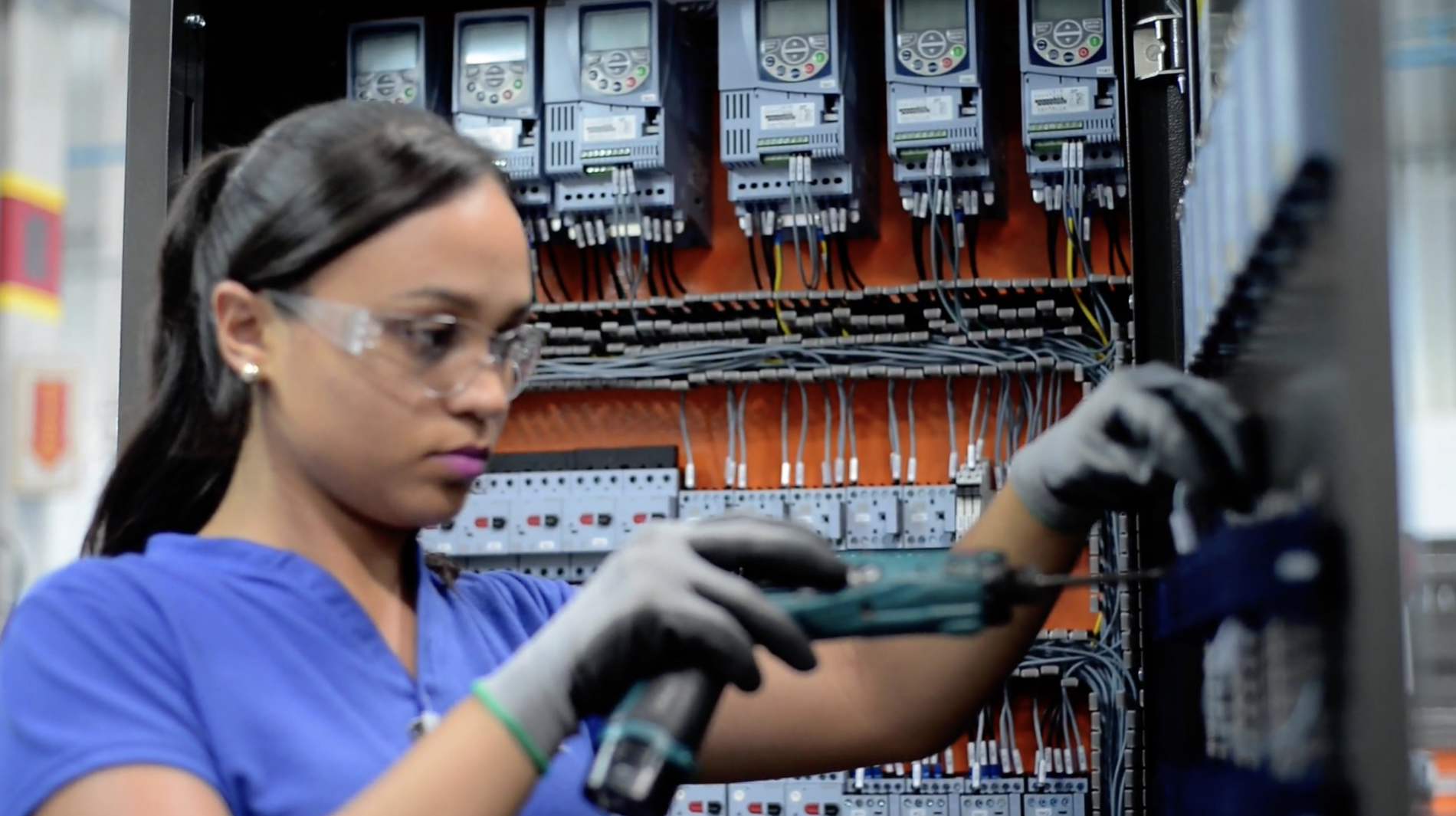 Female technician servicing an open electrical panel for AC motor and VFD configuration.
